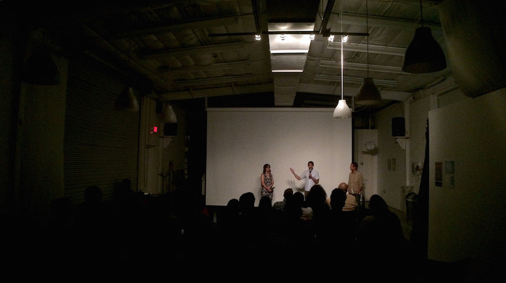 Three people stand in front of a large screen during the Q&A portion of a film screening.