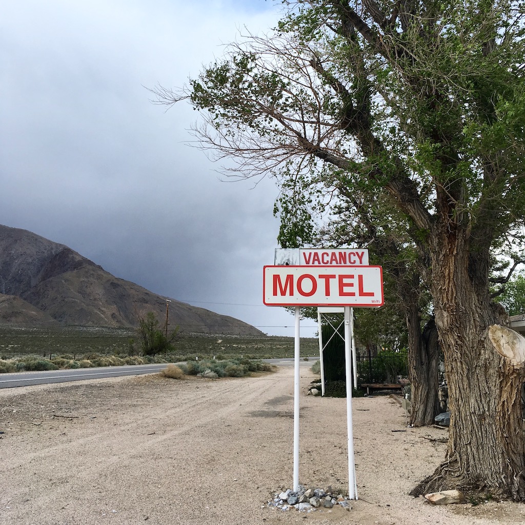 A sign by the side of an empty road reads, "Vacancy, Motel."