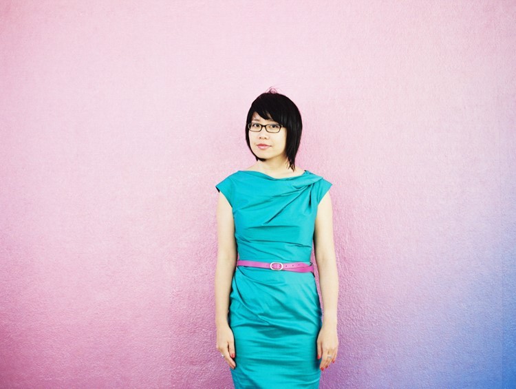Photo portrait of Melissa Hung, an Asian American woman, standing against a pink wall.