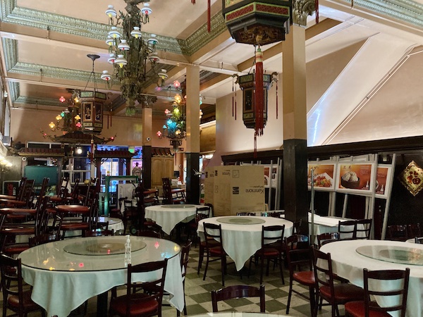 The dining room of a restaurant, empty of people, with chairs and signs stacked to the side