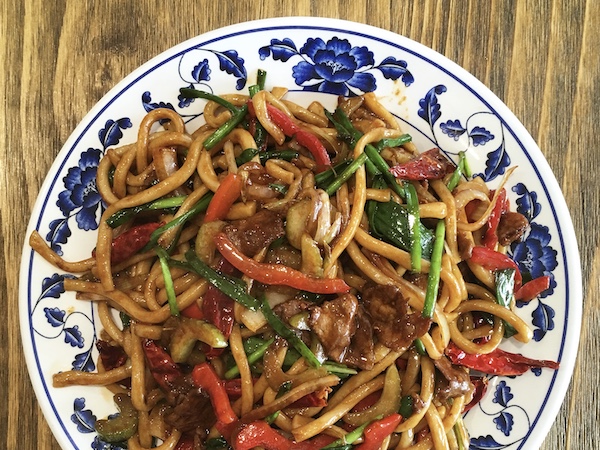 A plate with a blue floral pattern piled with hand-pulled noodles.